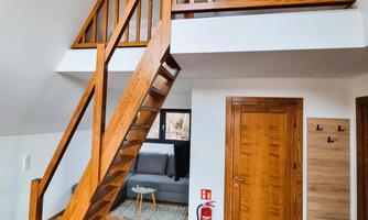 A modern interior view with a wooden staircase and bright walls. The room has a friendly, open character.
