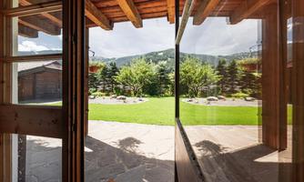 A beautiful view of a garden with green lawn and trees. In the background, gentle hills and a blue sky can be seen.