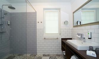 A modern bathroom with a shower, bright tiled floor, and elegant furnishings. The room is well-lit and offers a clean, fresh atmosphere.