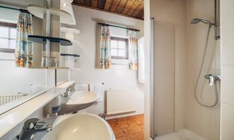 A modern bathroom with a shower area and a sink. Bright walls and wooden details give the space a cozy atmosphere.
