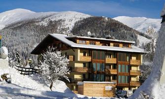 A cozy hotel nestled in a snow-covered landscape. The mountains in the background are majestic and the sky is clear.