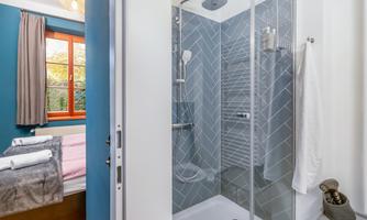 A modern bathroom with a shower and elegant tiles. The windows let in a lot of light and create a pleasant atmosphere.