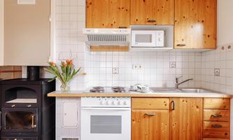 A modern kitchen with wooden fronts and white appliances. Fresh flowers and kitchen utensils are on the countertop.