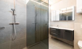A modern bathroom with a shower and large mirrors. The walls are in neutral shades of gray.