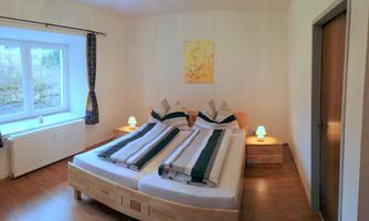 A cozy bedroom with two separate beds. The room has a window and soft light from bedside lamps.
