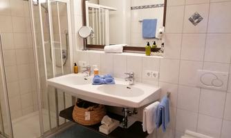 A modern bathroom with a shower and sink. Clean tiles and towels give the room an inviting atmosphere.