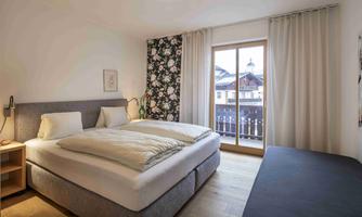 A cozy bedroom with a double bed and modern furnishings. Large windows provide a view outside and plenty of daylight.