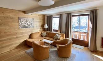 A cozy living room with a large window and a beautiful view. The furniture is in warm earth tones, and the room has an inviting character.