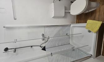 A modern bathroom with a shower cabin and a toilet. There is a yellow towel on the floor.