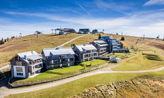A modern mountain hut in a picturesque landscape. Green meadows and clear skies surround the building.