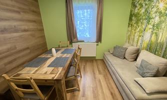A cozy room with a wooden table and chairs. On the wall, there is a green mural of a forest.