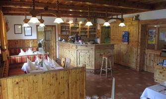 A cozy inn with wooden paneling and warm lighting. The tables are set and the bar is clearly visible.