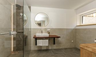 A modern bathroom with a glass shower and an elegant sink. The round mirrors and warm tones create an inviting atmosphere.