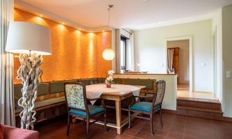 A cozy dining area with a table and chairs. The walls are painted in warm colors, and a lamp provides pleasant light.
