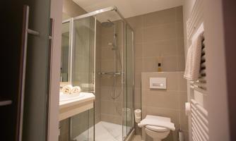 A modern bathroom with a shower, sink, and toilet. Towels and a hairdryer are also available.