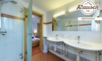 A modern bathroom with two sinks and a shower. Bright tiles and a clear mirror give the space an inviting atmosphere.