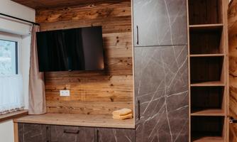 A modern room with a television on the wall. The furniture is made of wood and offers plenty of storage space.