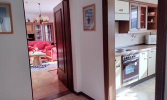 A bright apartment with a modern kitchen and a view of a living room with red sofas. The rooms are well designed and inviting.