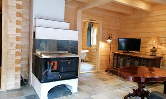 A cozy living space with a wood stove and wood paneling. The room is bright and inviting, with a table and a television in the background.
