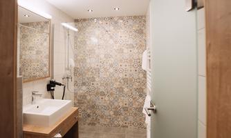 A modern bathroom with a stylish sink and a tiled wall. The lighting is bright and inviting for use.