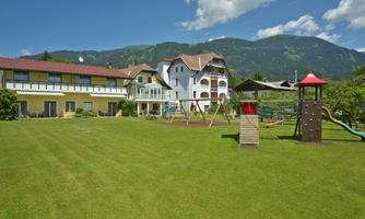 A beautiful playground with playground equipment in a green meadow. In the background, the mountains and buildings are visible.