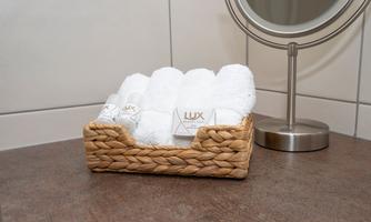 A basket with white towels is on a work surface. In the background, there is a round mirror.