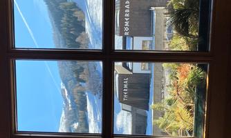 A view from the window of snow-covered mountains and a relaxing thermal spa. The buildings are modern and harmonize with the winter landscape.