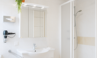 A modern bathroom with a shower and a sink. The walls are bright and the room is well lit.
