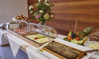 A rich breakfast buffet with fresh bread, fruit, and jam. The table also features honeycombs and floral arrangements.