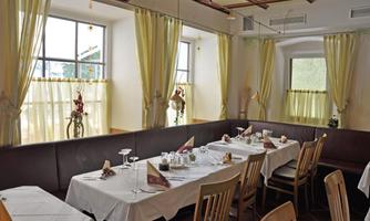 An inviting restaurant with tables set for guests. The windows are adorned with yellow curtains, and there is a bright, friendly atmosphere.