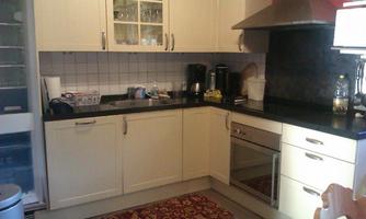 A modern kitchen with bright cabinets and black countertops. In the background, various kitchen appliances and dishes are visible.