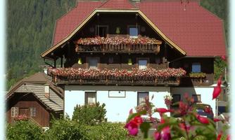A charming multi-story house with a red roof and romantic flower boxes. Surrounded by a beautiful green landscape.