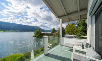 A cozy terrace overlooking a lake with mountains in the background. The landscape is peaceful and inviting.
