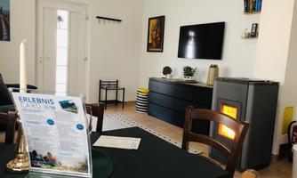 A cozy living space with a modern fireplace and a TV on the wall. On the table lies an experience card and a candle.