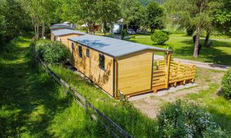 A modern wooden accommodation surrounded by green landscape. The accommodation has a terrace and is situated in a quiet environment.