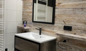 A modern bathroom with a wood panel wall design and an elegant sink. The space is well-lit and features practical shelving.