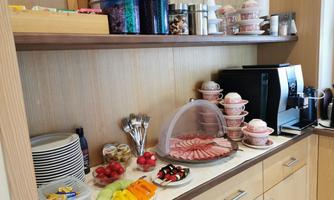 A small kitchenette with various foods and drinks. There is fresh fruit, snacks, and a coffee machine.