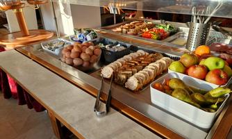 A rich breakfast buffet with fresh fruit, sausages, eggs, and various high-quality dishes. The display is inviting and well-arranged.