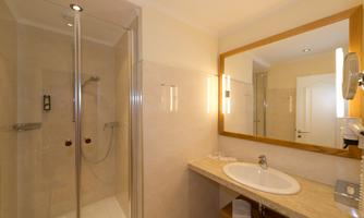 A modern bathroom with a shower and an elegant sink. Bright walls and a large mirror create a friendly atmosphere.