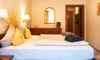 A comfortable room with a double bed and stylish decorative elements. The warm colors and natural light create an inviting atmosphere.