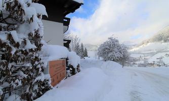 A snow-covered landscape with a two-story building and a deep blanket of snow. The impressive mountain backdrop is visible in the background.