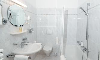 A modern bathroom with a bathtub and a shower. The walls are brightly tiled, and there is a large mirror.