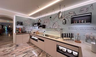 A modern kitchen unit with elegant furniture and an appealing wall design. Various drinks and dishes are attractively arranged on the countertop.