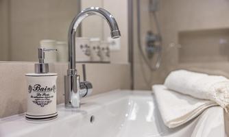 An elegant bathroom with a modern faucet and a soap dispenser in a stylish container. Fresh towels are placed next to the sink.