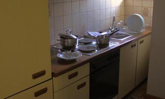 A small kitchen with neutral colors and a windowsill. Pots and dishes are visible on the countertop.