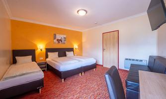 A bright room with two single beds and a chair. A picture hangs on the wall, and there is a television as well as a table.