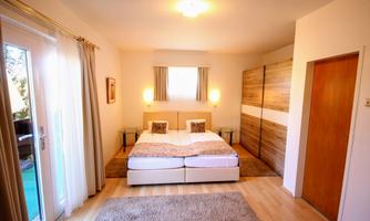 A bright and modern bedroom with two beds and elegant furniture. Large windows provide plenty of daylight and an inviting atmosphere.