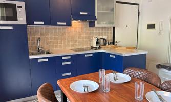 Modern kitchen with blue cabinets and a cozy dining area. The table is set with plates and glasses.