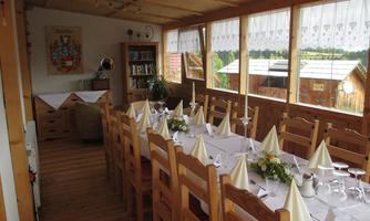 An inviting dining area with long wooden tables and chairs. The room is bright and has large windows that offer a view of nature.