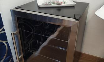 A small refrigerator with glass doors stands in the corner. On it, there is a tray with glasses.
